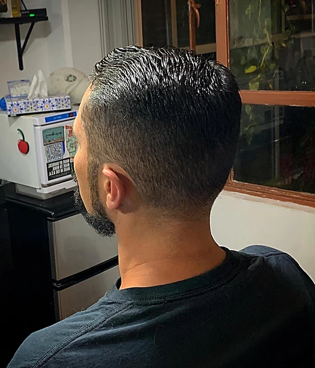 Cliente de espaldas con corte corto y barba delineada.