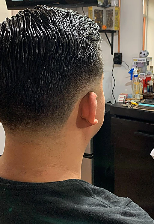 Corte clásico con degradado bajo y peinado con brillo hacia atrás.